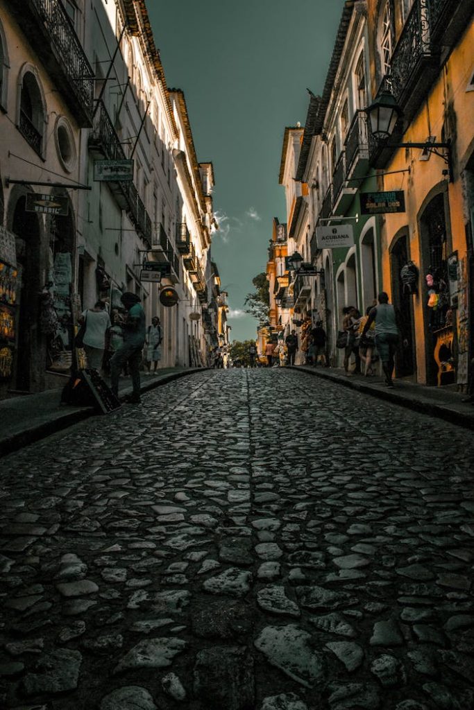 Explore historic cobblestone streets lined with lit buildings in an enchanting evening setting.